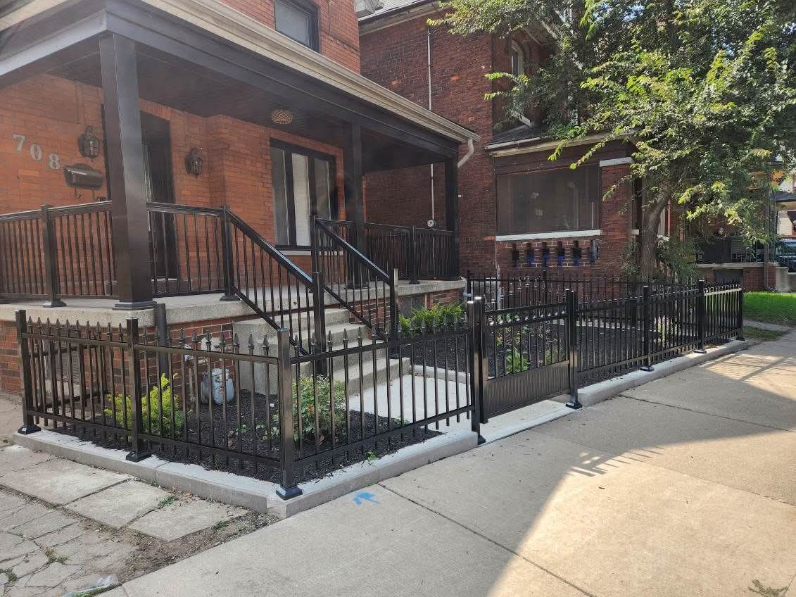 Black metal fence and matching porch railings installed on a red brick home.